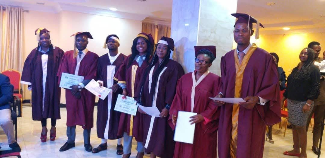 Bible School graduates in academic gowns holding their certificates